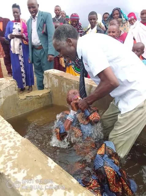 Men assisting a woman at an outdoor baptism