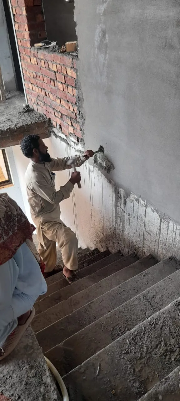 Worker plastering a stairwell wall