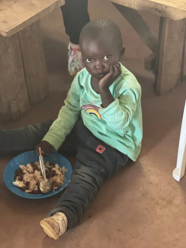 Child eating from a plate while seated on a bench