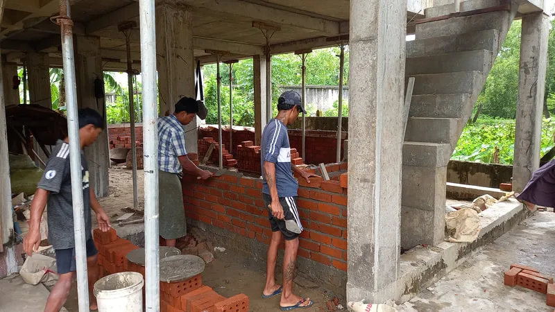 Workers building interior brick walls