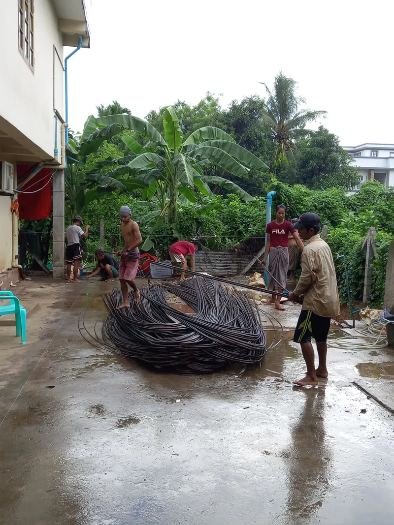 Workers moving a coil of steel reinforcement