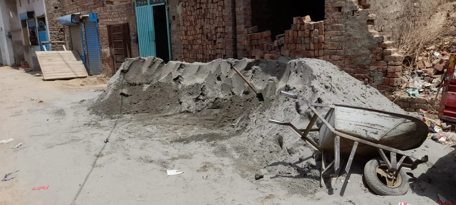 Sand and a wheelbarrow beside a brick building