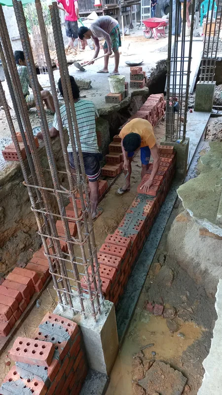 Masons laying bricks beside column reinforcement