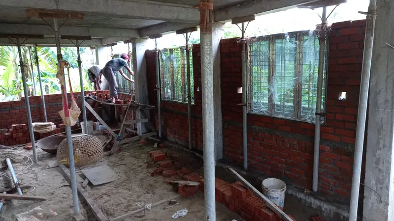 Workers laying brick walls inside a building