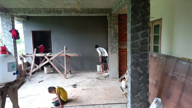 Workers plastering interior walls