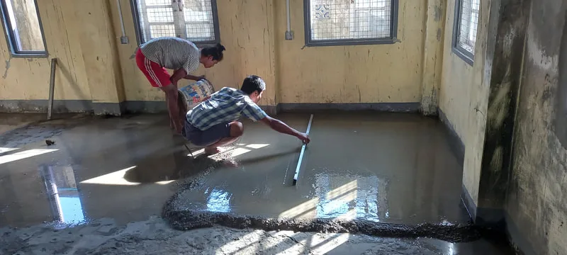 Workers smoothing a wet concrete floor
