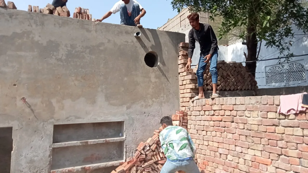 Workers building and plastering the walls of a brick building