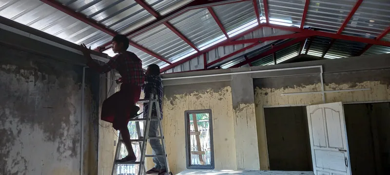 Worker adjusting a roof support from a ladder