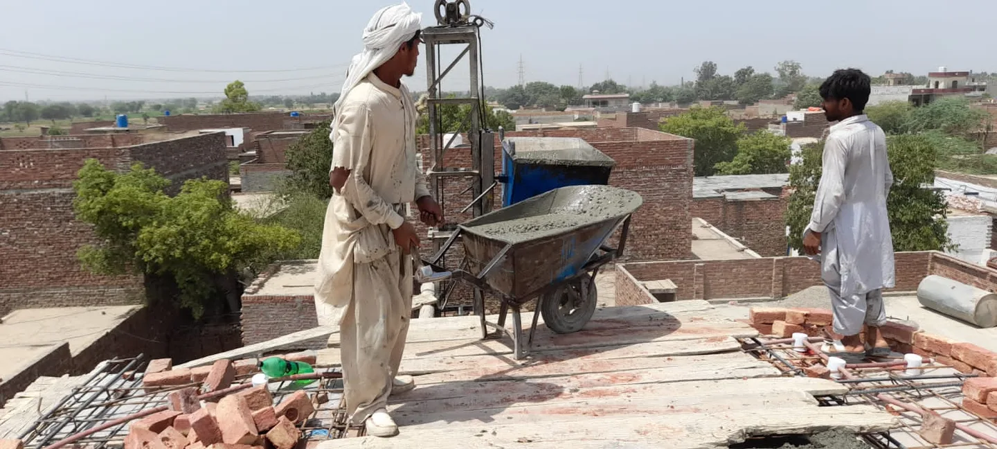 Workers beside a wheelbarrow on a roof