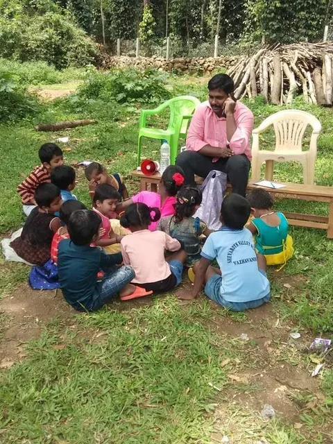 An adult seated with a small group of children outdoors
