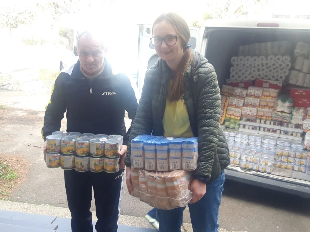 People carrying food supplies beside a van