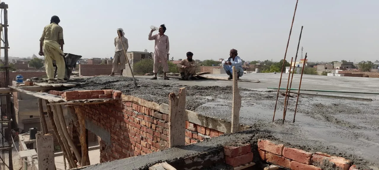Workers preparing concrete along the edge of a roof