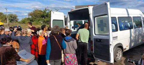 People receiving supplies beside a minibus