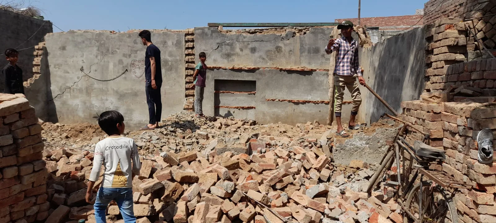 Workers standing among bricks inside a partially built room