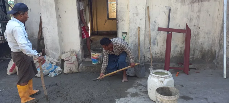 Workers leveling a concrete floor indoors
