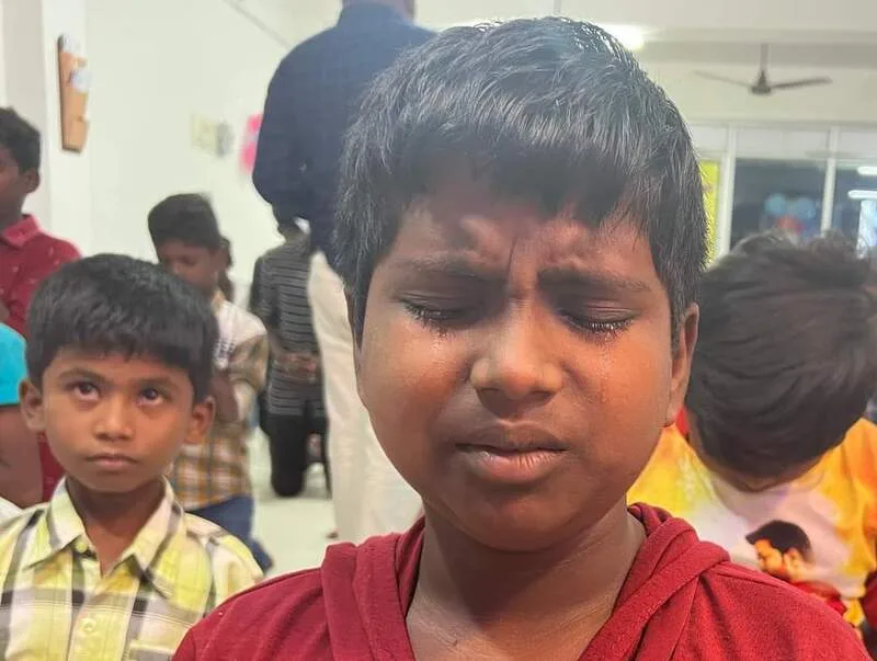 A child standing among other children with eyes closed