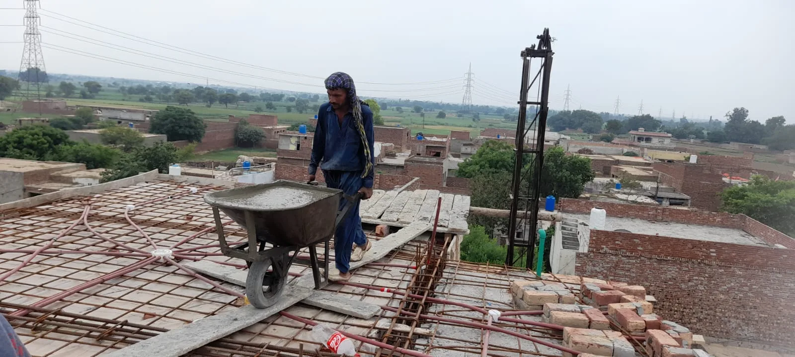 Worker standing beside a wheelbarrow on a roof
