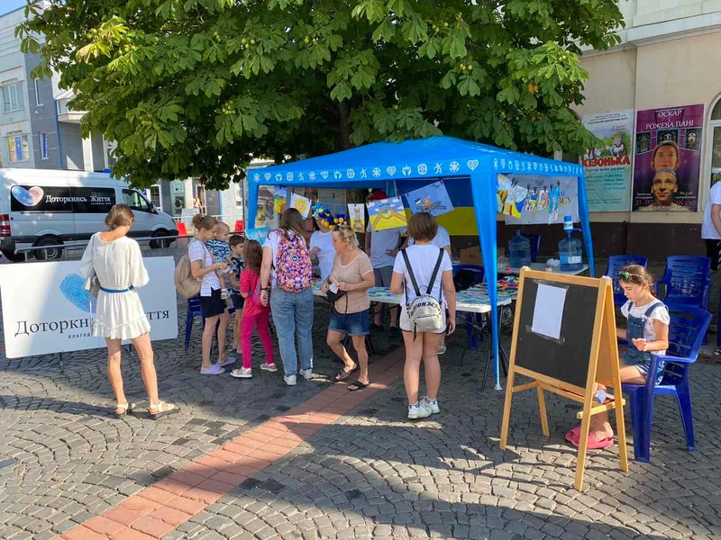 People gathered at a blue outdoor information stall
