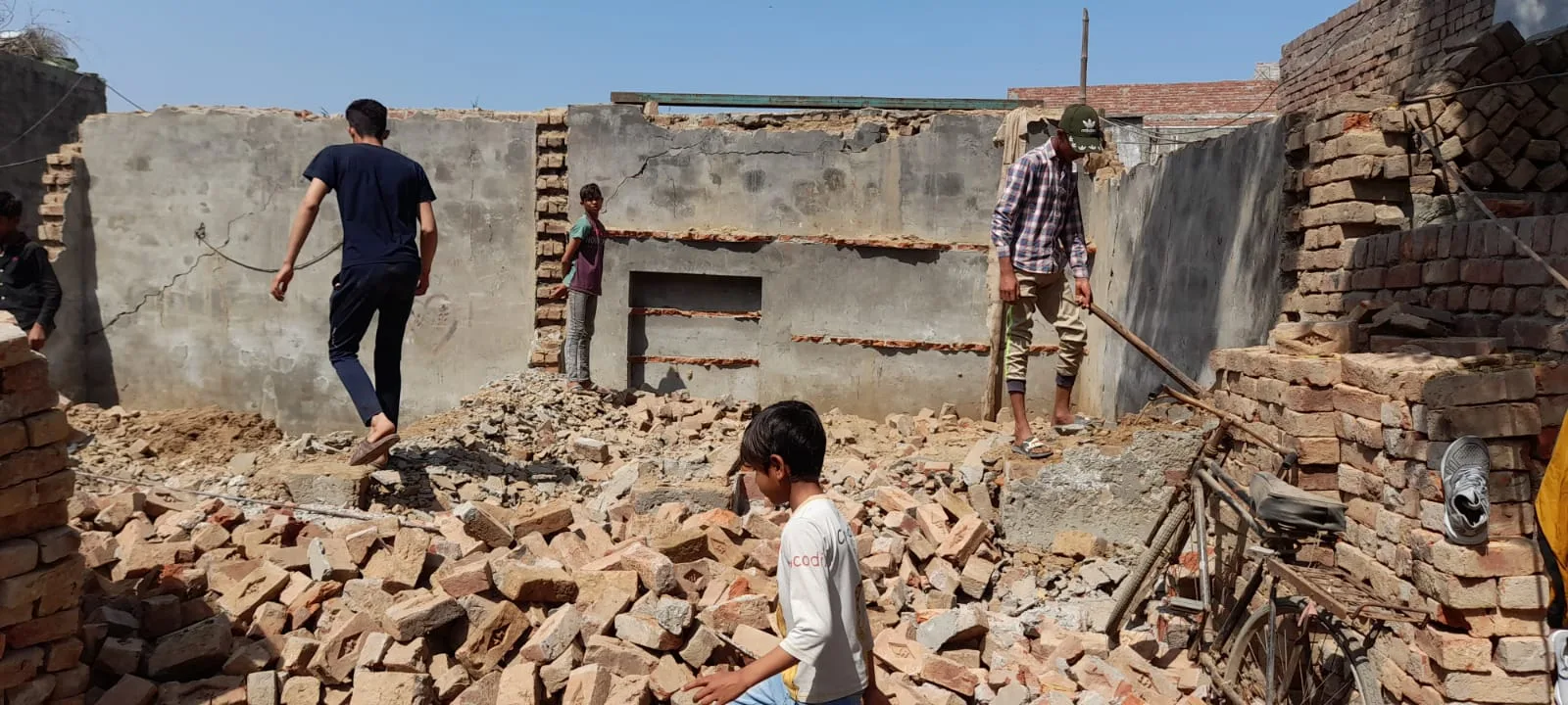 People among the remains of a damaged brick building