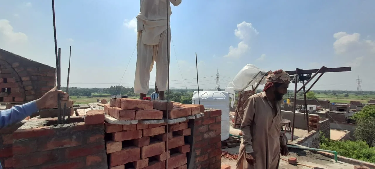 Workers building decorative brickwork on the roof