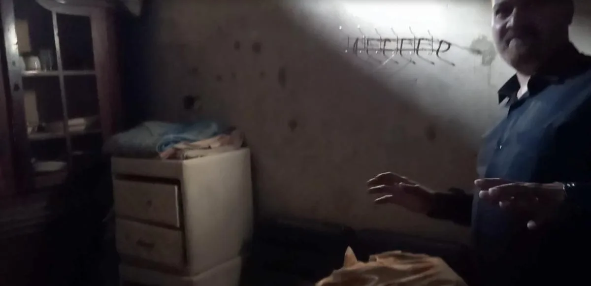 A man showing a small room with beds and furniture