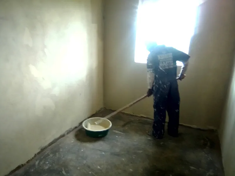Worker smoothing the base of an interior wall