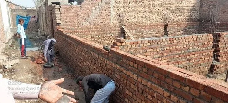 Workers constructing brick foundation walls