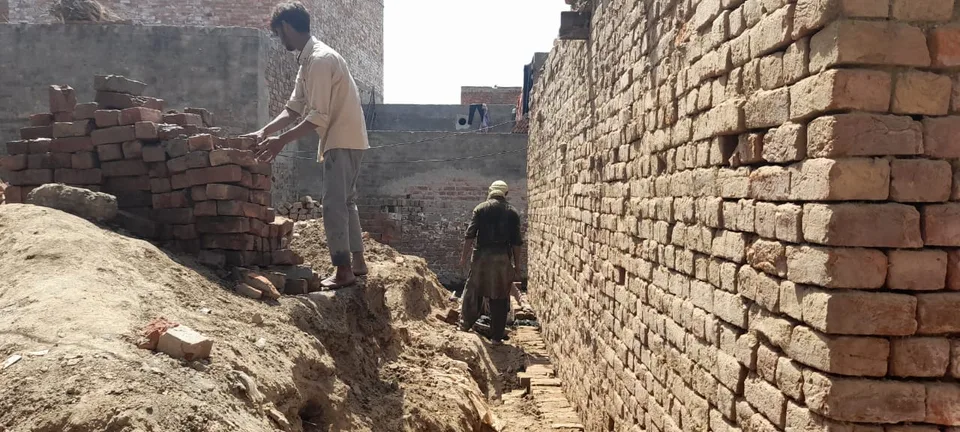 Workers digging beside a brick wall