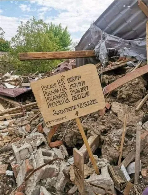 Memorial marker amid rubble and damaged buildings