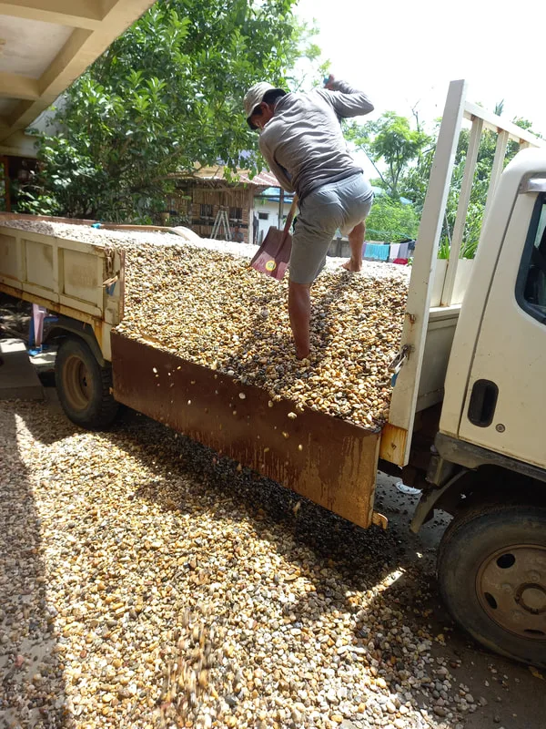 Worker unloading gravel from a flatbed truck