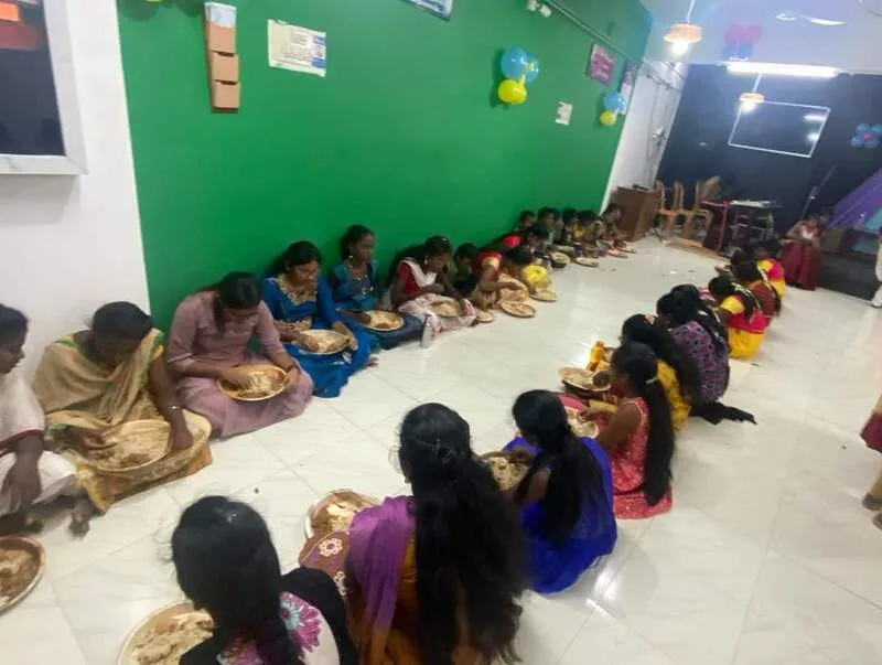 Children seated along a wall eating a meal together