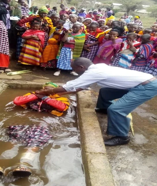Outdoor baptism with people gathered alongside
