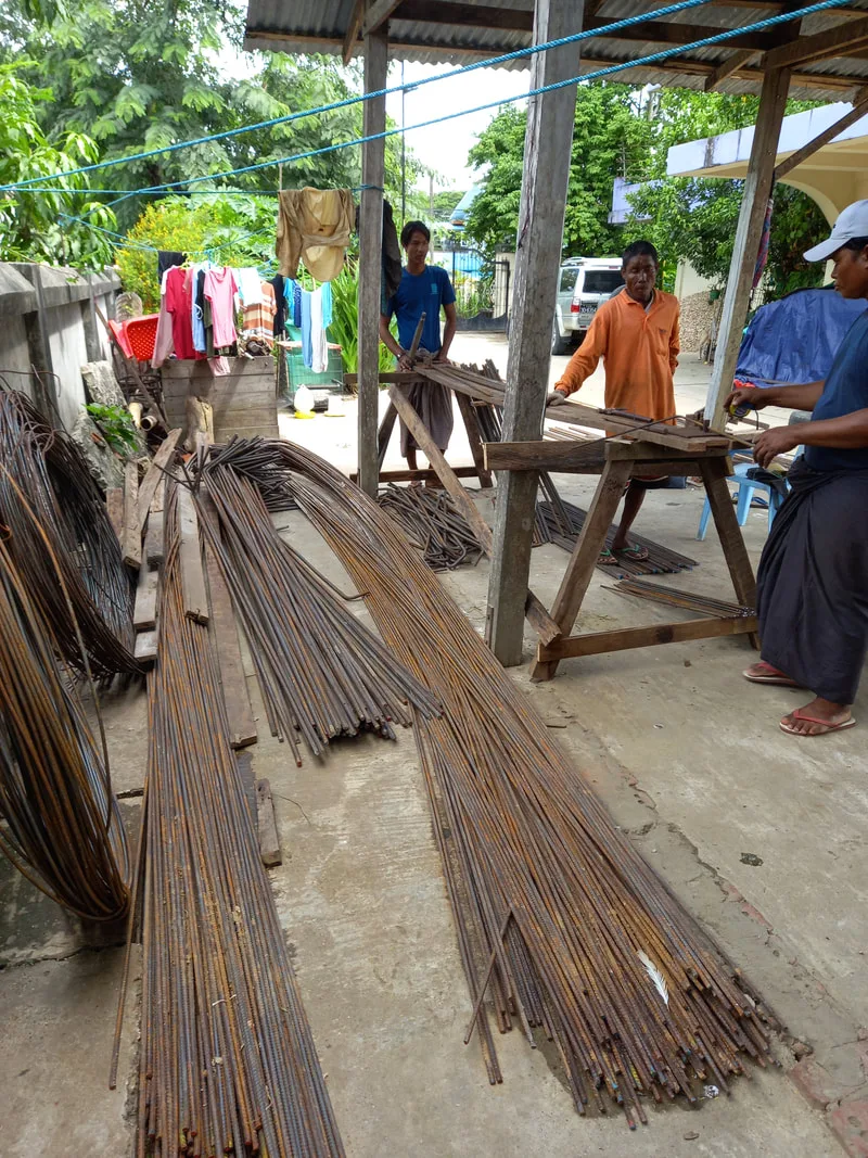 Steel reinforcing rods stacked beside a building