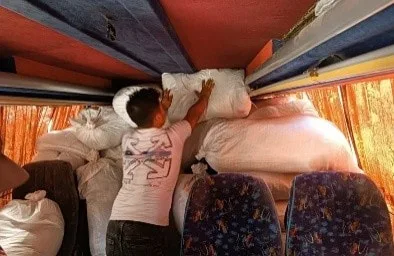 A man arranging large sacks inside a bus