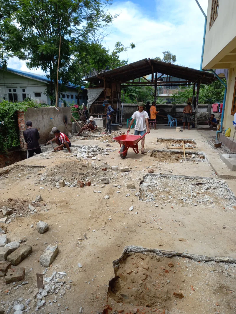 Workers preparing ground beside a building