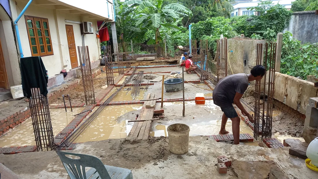 Workers preparing ground between foundation columns