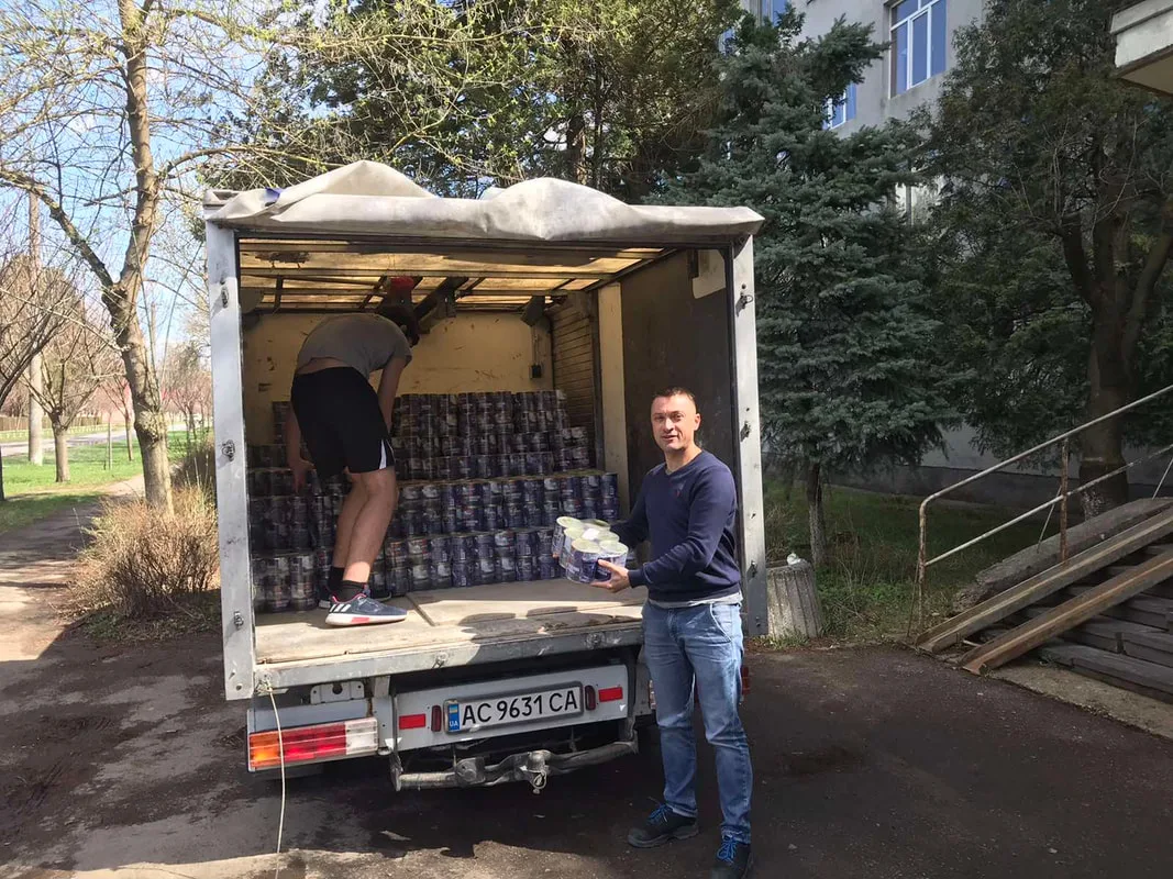 Two men beside a van loaded with supplies