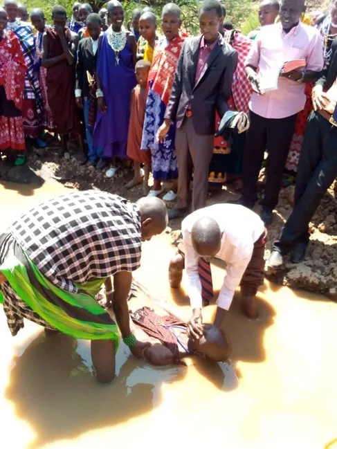 People gathered around an outdoor baptism