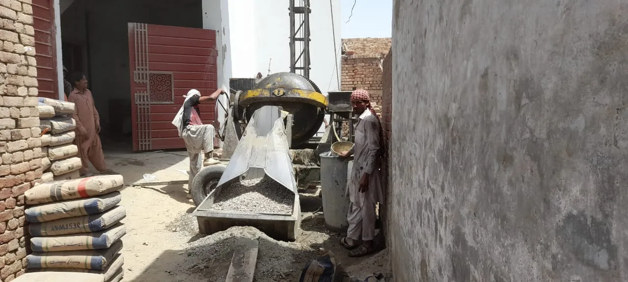 Concrete mixer dispensing material beside a brick wall