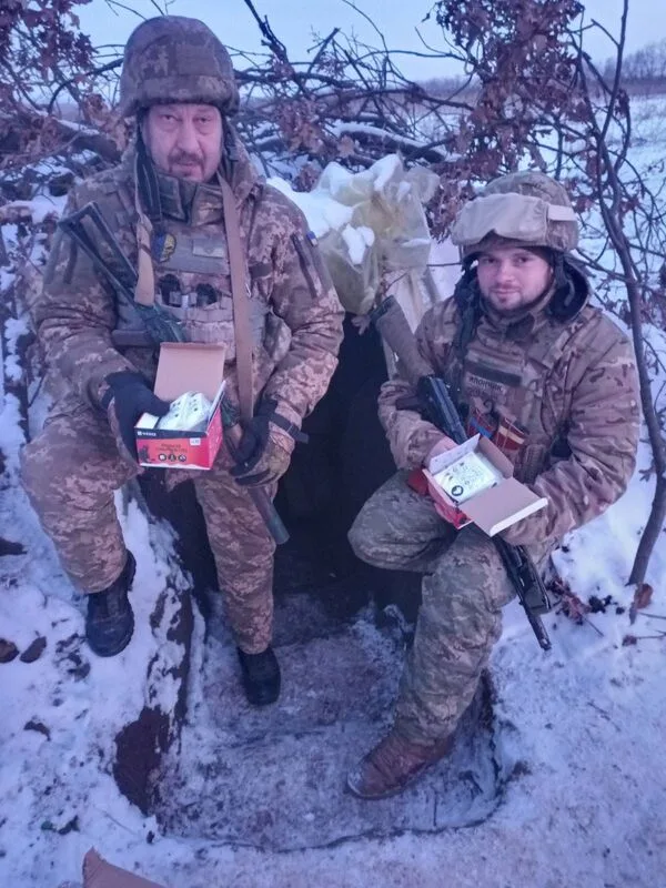 Two people holding small packages outdoors in snow