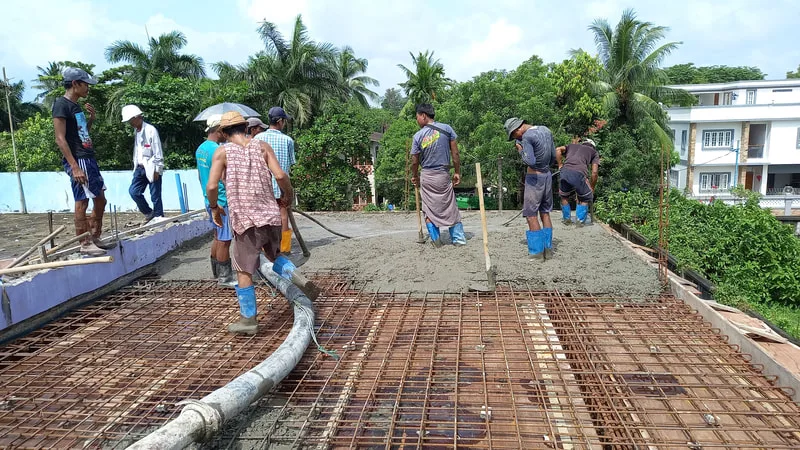 Workers pouring concrete for an upper floor
