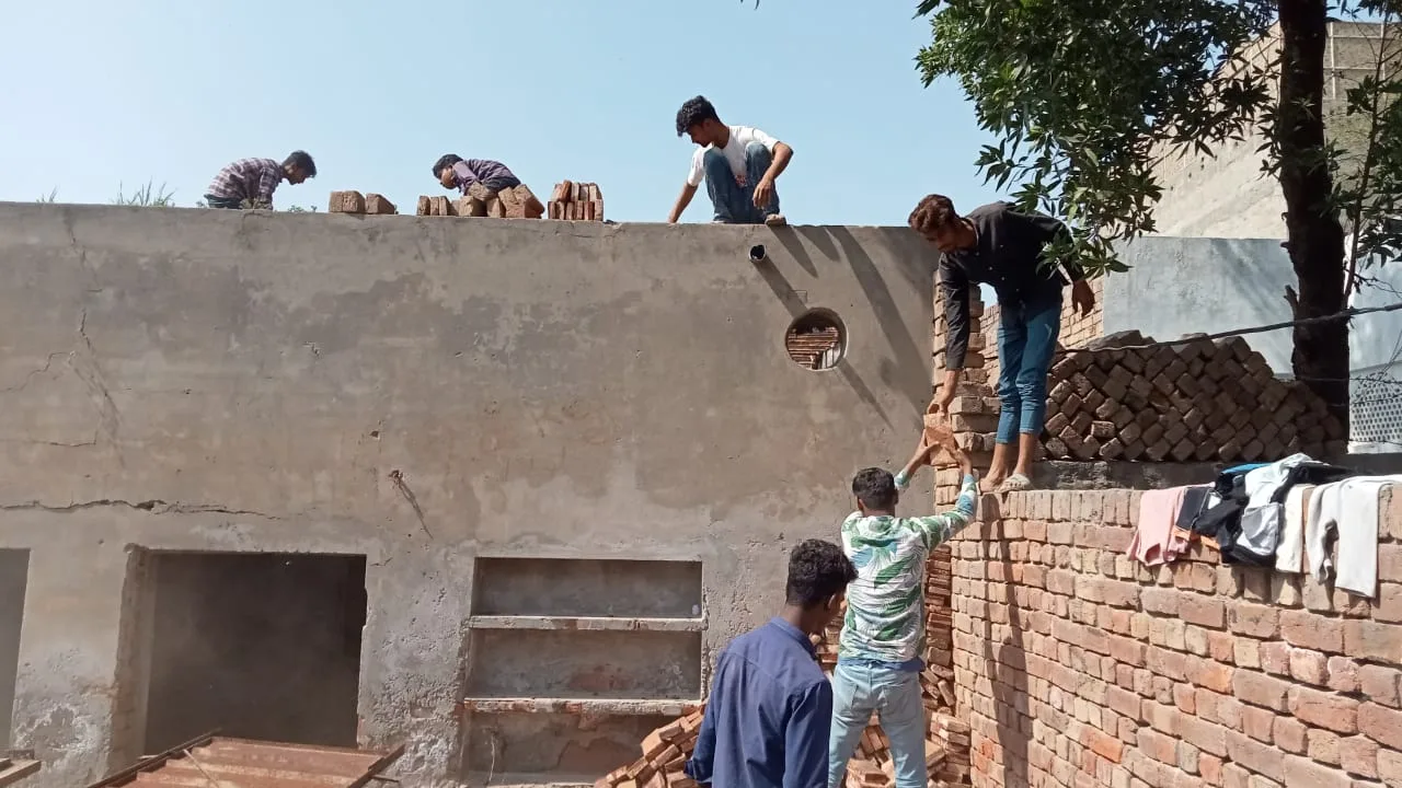 Workers finishing the roof and walls of a brick building