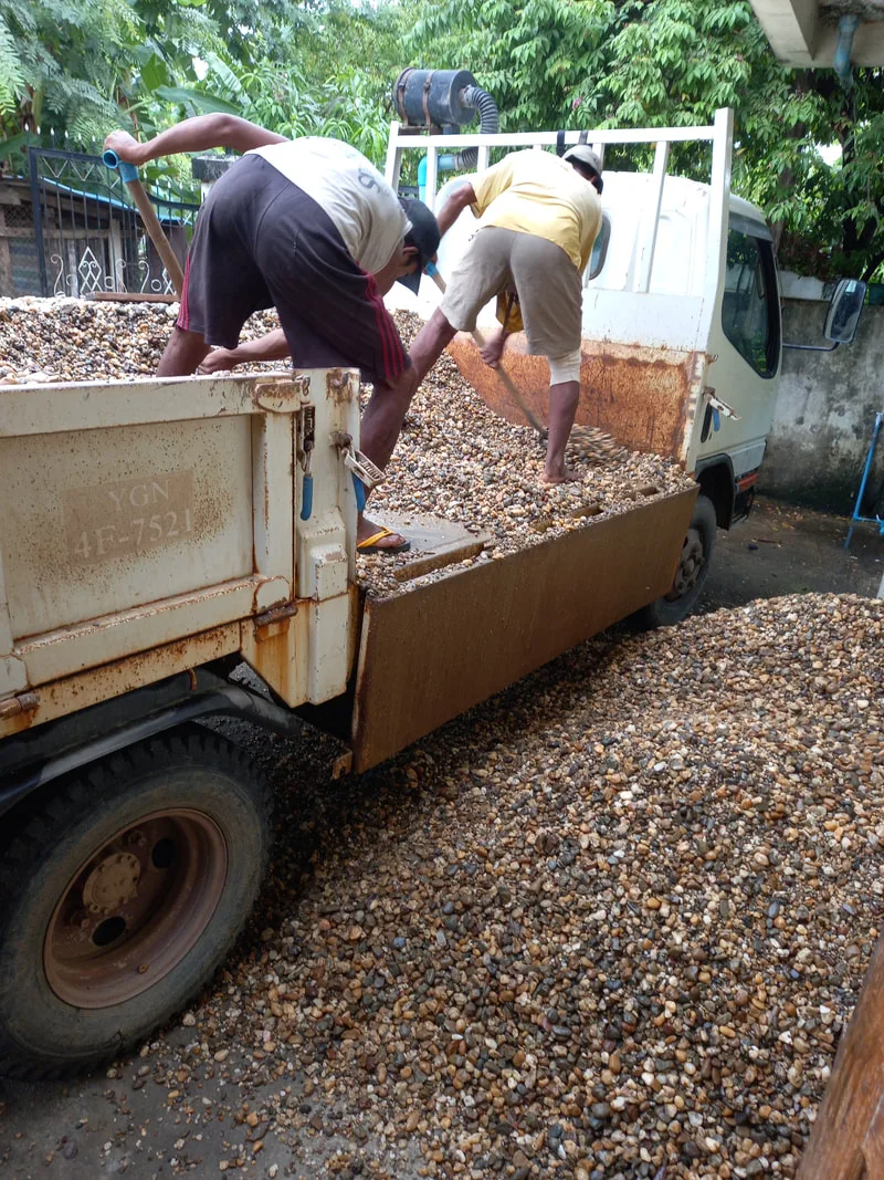 Workers unloading gravel from a truck