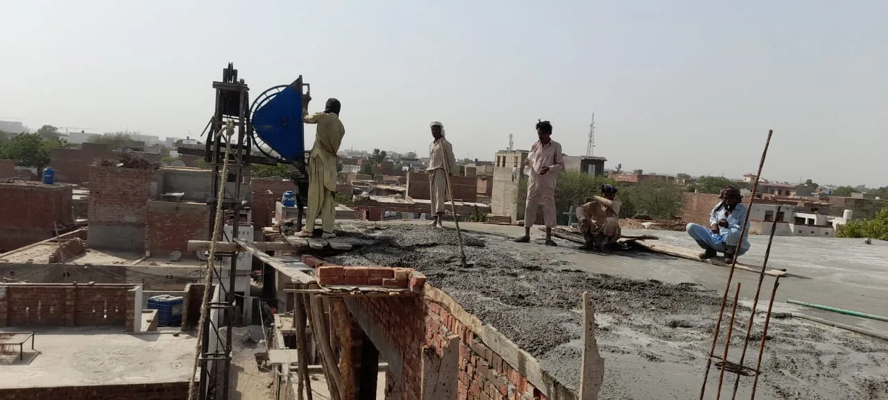 Workers beside a material lift on a roof