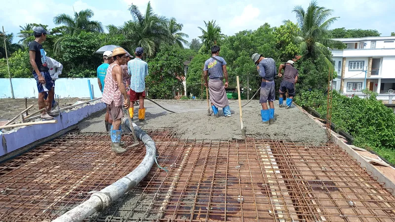 Workers leveling concrete on an upper floor