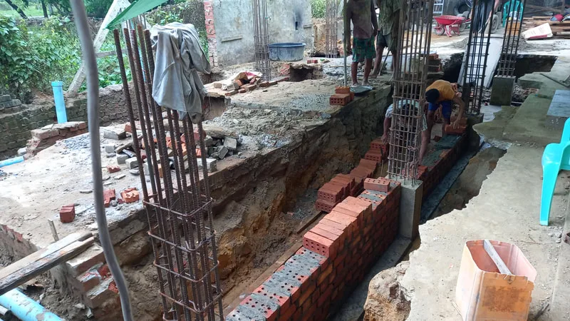 Workers laying brick foundation walls