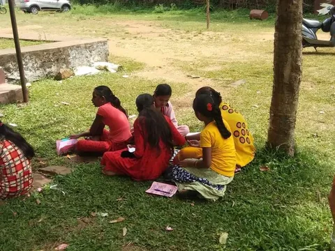 Children seated on the grass with books in their laps