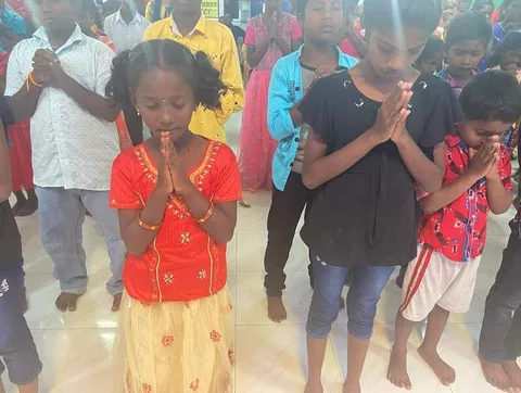 Children standing together with their hands clasped