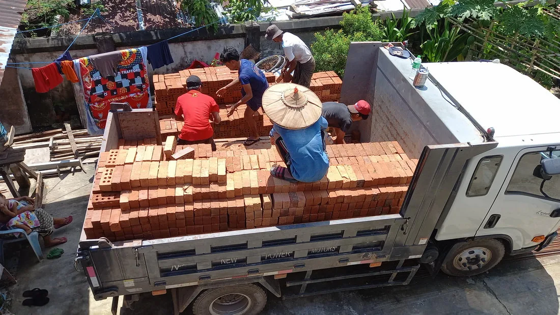 Workers unloading bricks from a truck