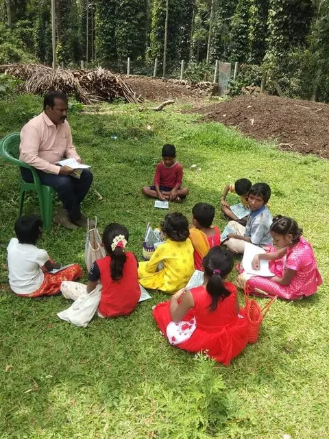 An adult sitting with children in a circle outdoors